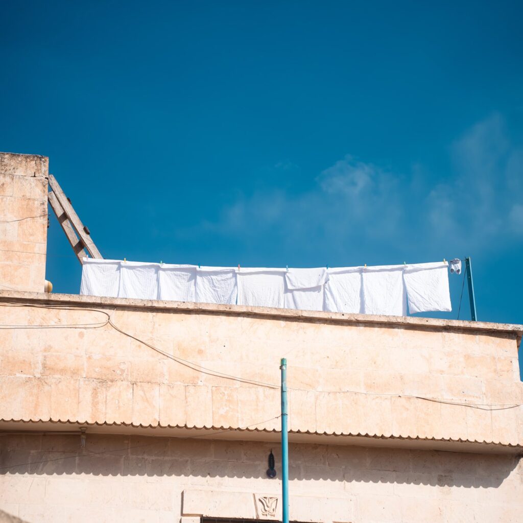 White laundry drying on a rooftop line beneath a clear blue sky.