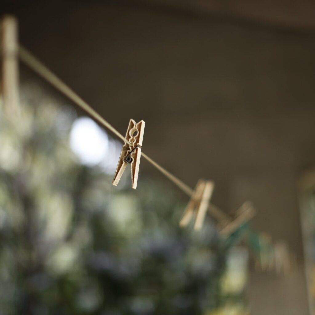 A wooden clothes peg on a diagonal drying line with softly blurred pegs behind it.