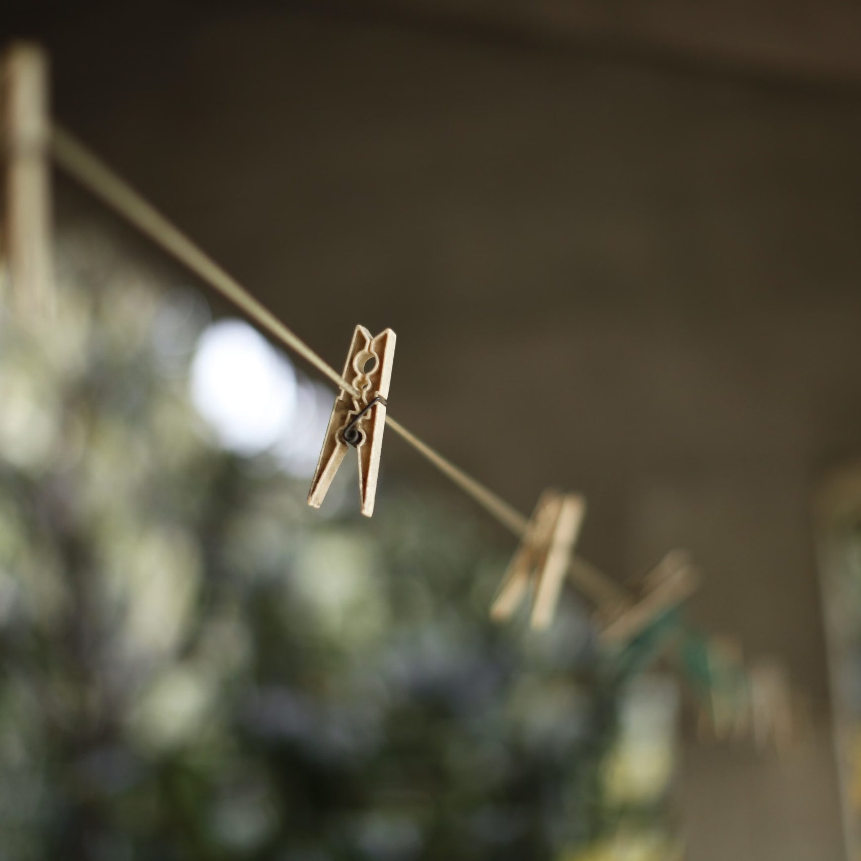 A wooden clothes peg on a diagonal drying line with softly blurred pegs behind it.